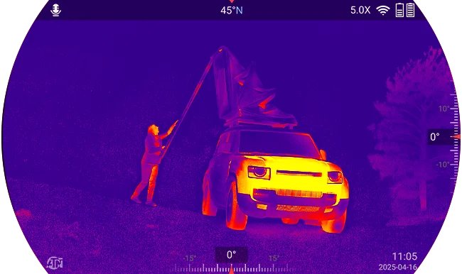 Thermal mode screenshot from the ATN Binox 6 Dual showing a person beside a vehicle at night with heat signatures in a purple, orange and yellow palette and on-screen compass and zoom data