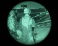 Point-of-view image through night vision goggles showing two people in tactical gear rendered in green phosphor