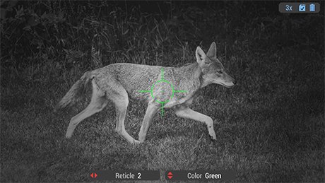 Screen view through a digital scope's night vision mode showing a coyote in a grassy field with a green digital reticle centered on the animal