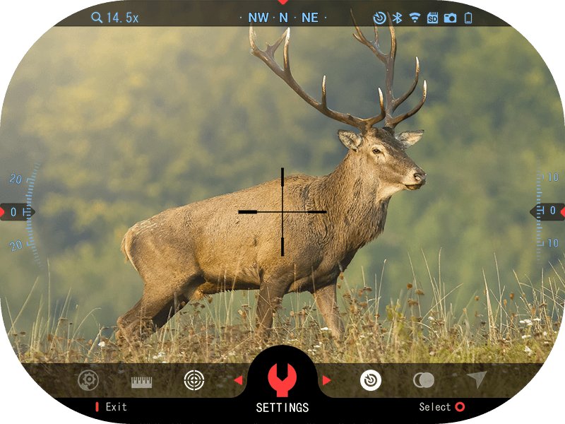View through the ATN X-Sight 5 in day mode showing a stag in a field with reticle and range data on screen